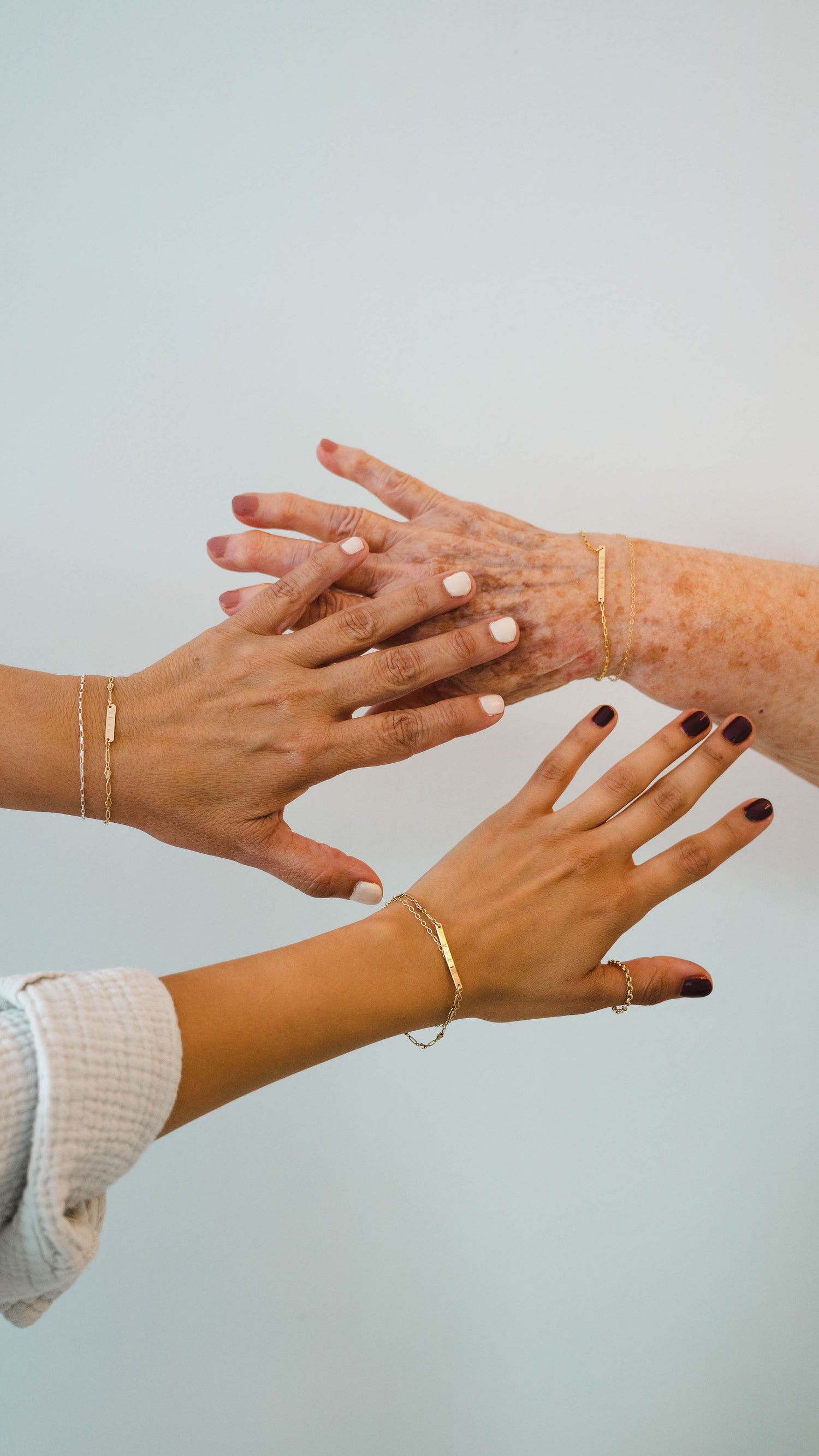 a picture of three generations of woman holding up their hands to show their permanent jewelry bracelets from APT. 144 Jewelry Studio